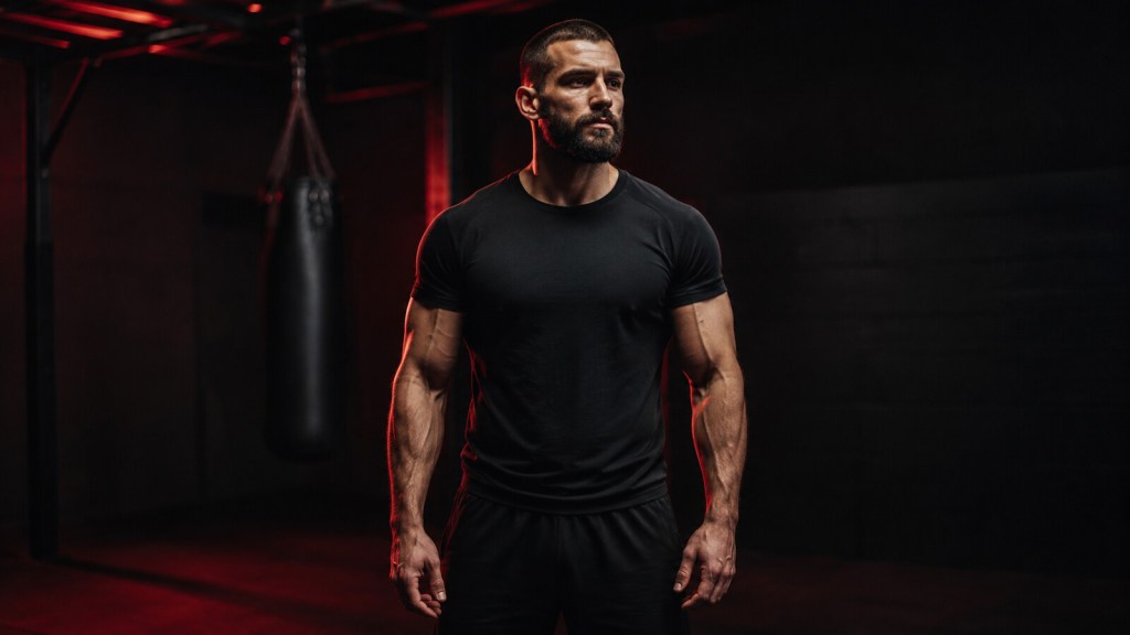 Composed man regulating his anger in a dark training room with dramatic black-and-red lighting