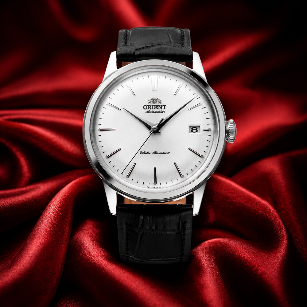 Orient Bambino Version 7 white-dial dress watch displayed on deep red silk